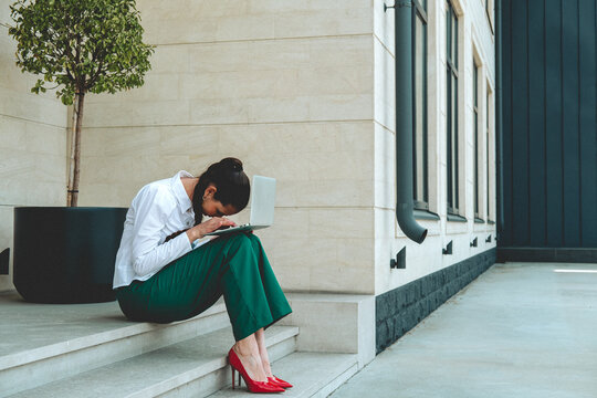 Stressed freelancer working on laptop sitting on outdoor steps