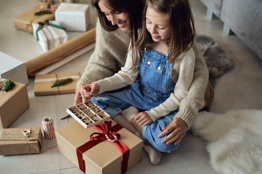 Smiling girl and mother with decoration box packing gift at home