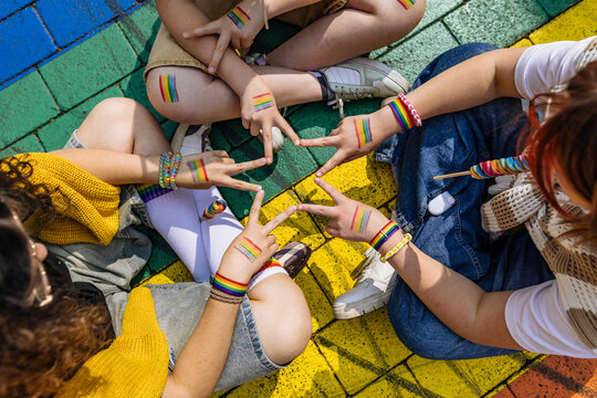 Friends with painted rainbow hands showing peace sign outdoors