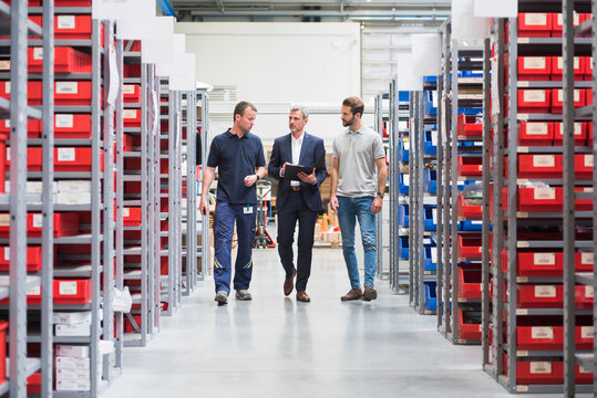 Three men talking in storehouse of a factory