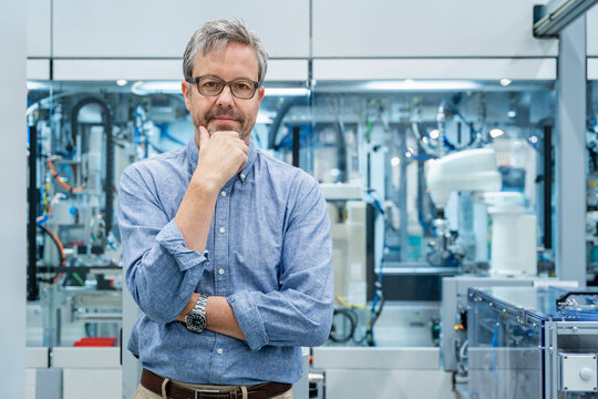 Engineer in factory portrait with automation and industrial robots