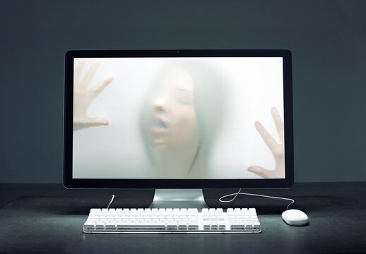 Human face and hands trapped inside a computer screen in cyberspace
