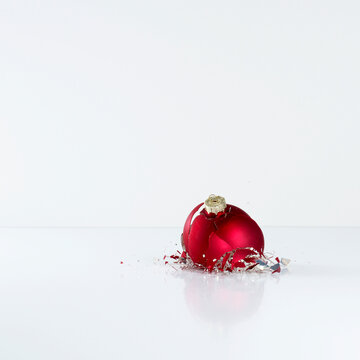 Broken red Christmas tree bauble shattering on white background