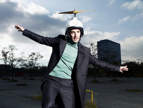 Businessman in propeller helmet pretending to fly outdoors