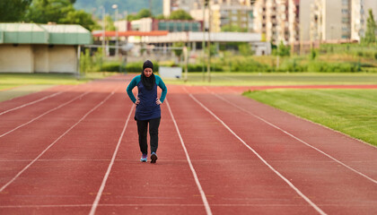 Obraz premium Muslim Woman Jogging on Outdoor Running Track Wearing Hijab and Sportswear for Fitness