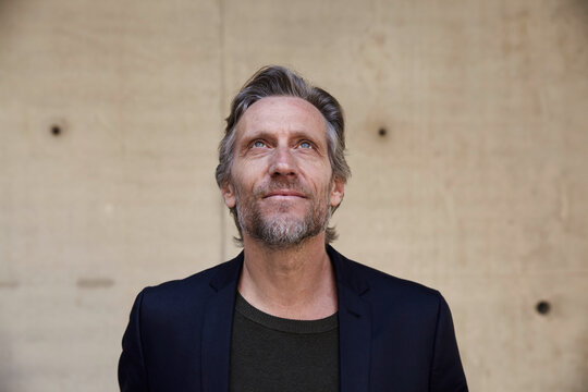 Portrait of confident mature man at concrete wall looking up