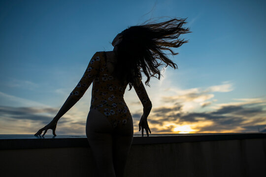 Silhouette against sunset sky with wind blowing hair
