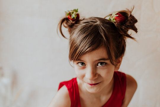 Smiling portrait with strawberries in pigtails indoors