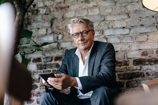Businessman sitting in cafe, using smartphone