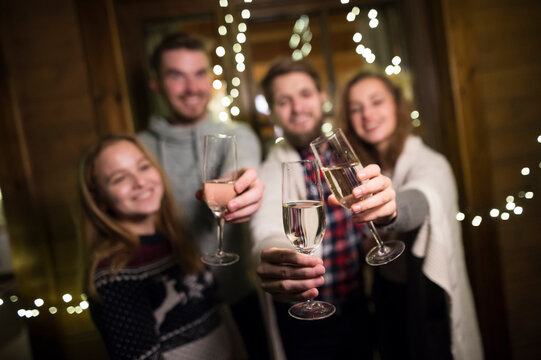 Happy friends holding champagne glasses outdoors at night