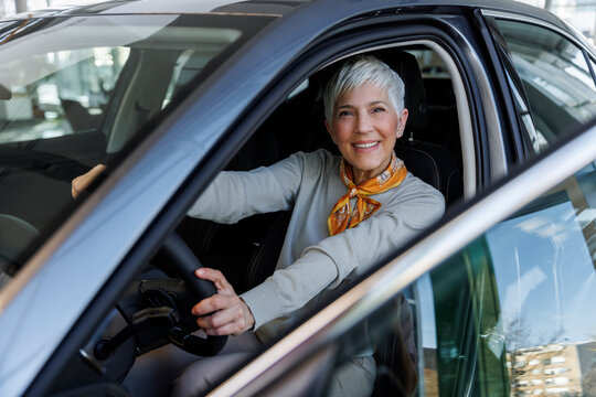 Happy senior woman sitting in car
