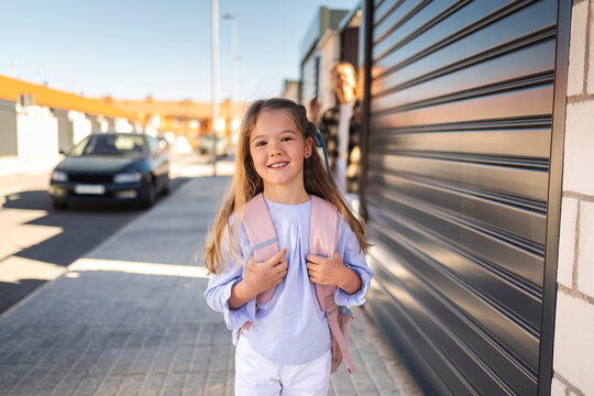 Happy daughter with backpack returning home from school to mother