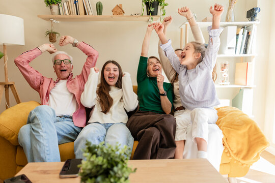 Excited family cheering while watching television at home