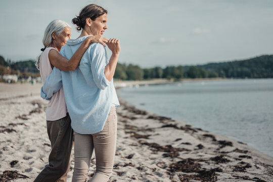 Mother and daughter spending a day at the sea, embracing on the beach