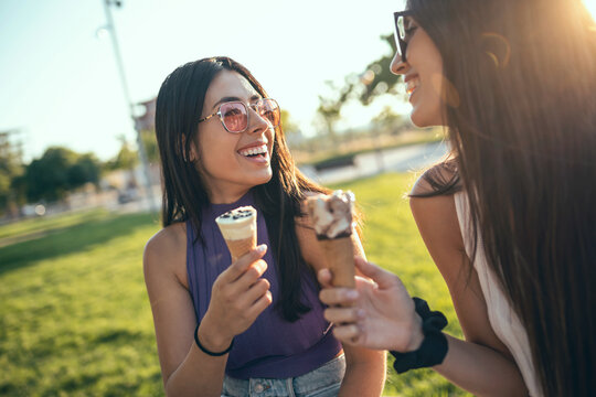 Smiling friends eating ice cream outdoors at the park