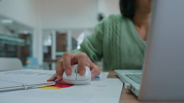 Close up hand's woman using wireless computer mouse working online on laptop computer at office desk.