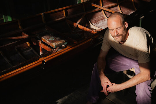 Man enjoying a tranquil break in sunny workshop with wooden boat