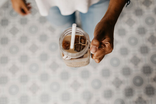 Hand of woman holding glass of iced coffee i