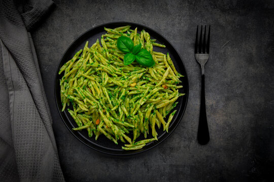 Trofie pasta with pesto alla genovese and basil on a dark table