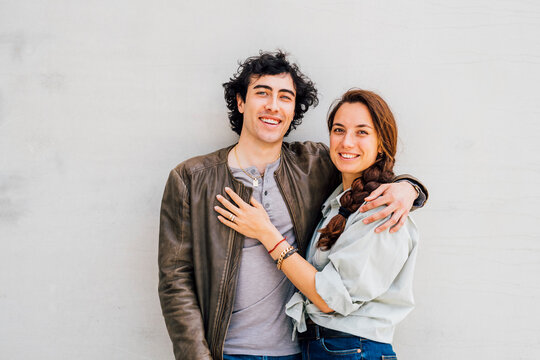 Smiling couple standing together in front of white wall