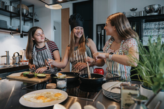Girlfriends preparing healthy lunch together, frying eggs in kitchen