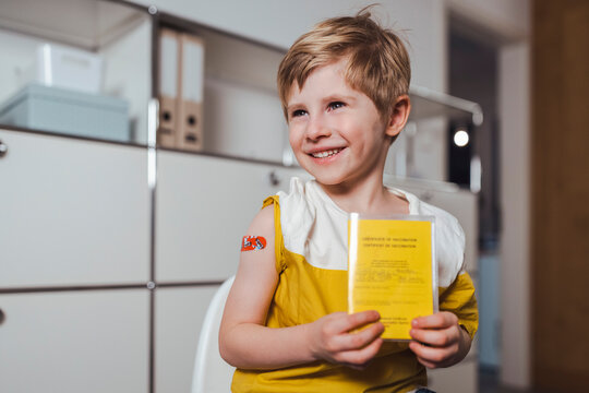 Smiling boy holding vaccination certificate at center