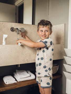 Smiling boy brushing teeth at modern bathroom sink