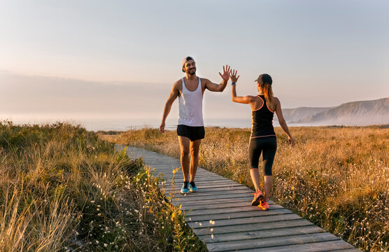 Spain, Aviles, athletes couple hitting five on the beach in the evening