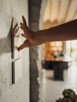 Hand pressing light switch in comfortable Tuscany bedroom