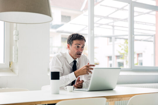 Shocked businessman looking at laptop on table in office