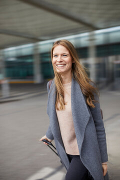 Portrait of confident businesswoman pulling suitcase at airport