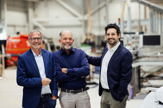 Three businessmen standing in a factory setting, showcasing teamwork and expertise