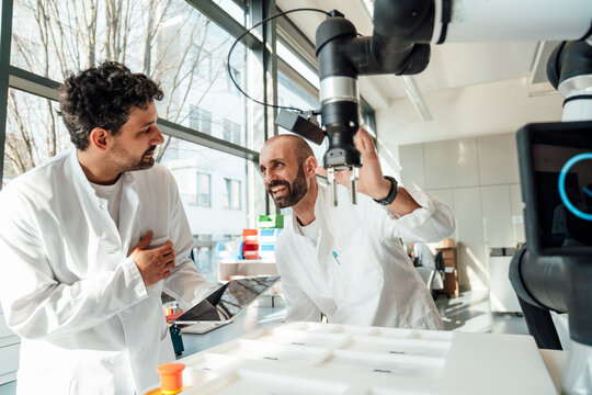 Scientist and colleague working with robot in laboratory
