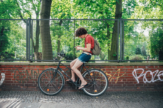 Young man using cell phone sitting on his bicycle