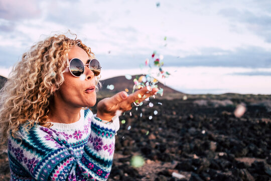 Blond woman blowing confetti in the air, Tenerife, Spain