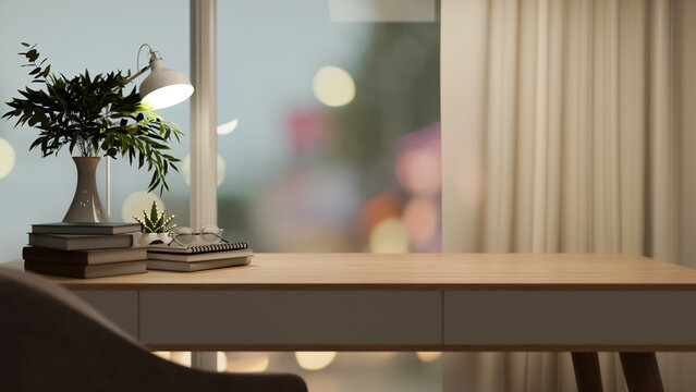 Eyeglasses over books with lamp and vase on wooden table beside window wall with blurred city view.