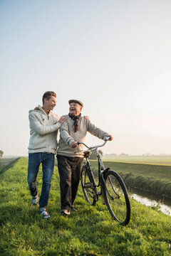 Senior man and grandson in rural landscape with bicycle