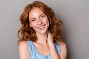 Naklejka premium The smiling woman with red hair posing confidently in a studio portrait with gray background