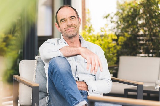 Relaxed man sitting on chair at backyard