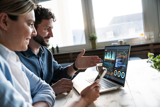 Business team analyzing financial data on laptop in office