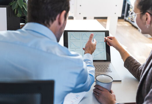 Business colleagues analyzing chart on laptop at the office