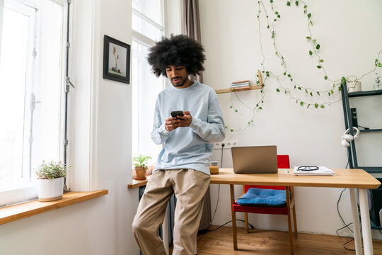 Young freelancer using mobile phone at home office