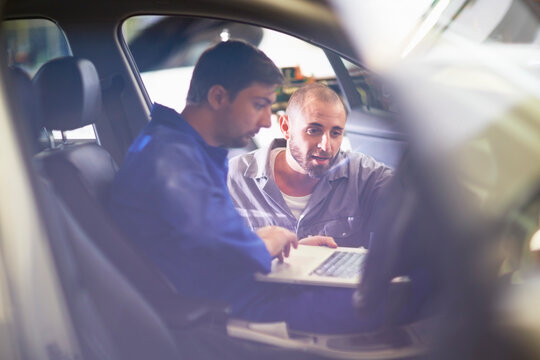 Two car mechanics with laptop in repair garage