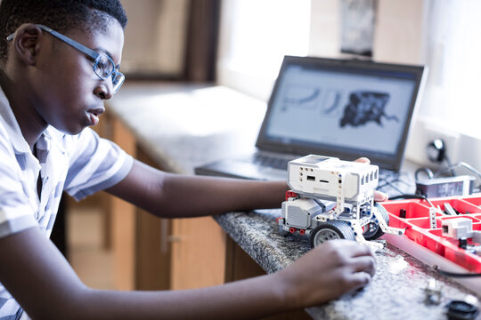 Schoolboy with laptop in robotics class