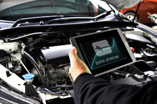 Mechanic diagnostics engine car using digital obd2 scanner tablet with data stream software at auto repair shop
