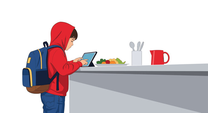 Young boy wearing a red hoodie and a backpack using a tablet while standing in the kitchen before school.