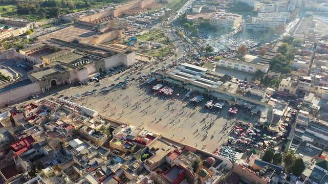 Drone aerial view of El Hedim Square and Bab Mansour, two of the most iconic landmarks of Meknes, Morocco. The scene showcases the rich heritage of this historic imperial city, its vibrant public spac
