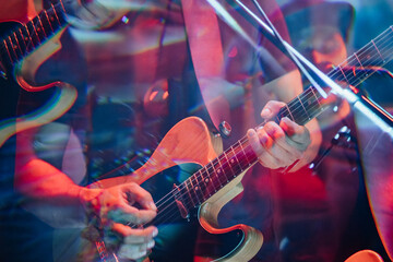 Naklejka premium Close-up of musicians playing electric guitars with colorful stage lighting, reflections, and energetic concert atmosphere