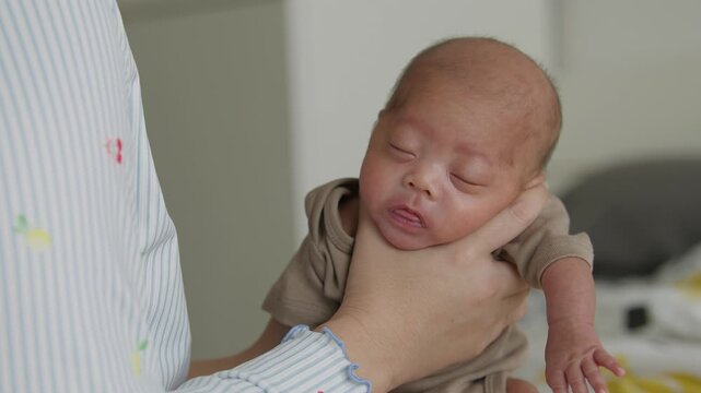 A mother's hands gently holding a newborn baby upright to burp after a full feeding, helping reduce reflux and prevent spit-up, infant care and parenting concept
