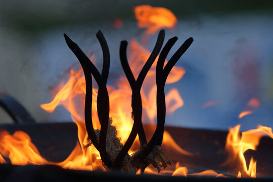 Close up of a dark abstract silhouette against bright orange burning flames in a fire pit